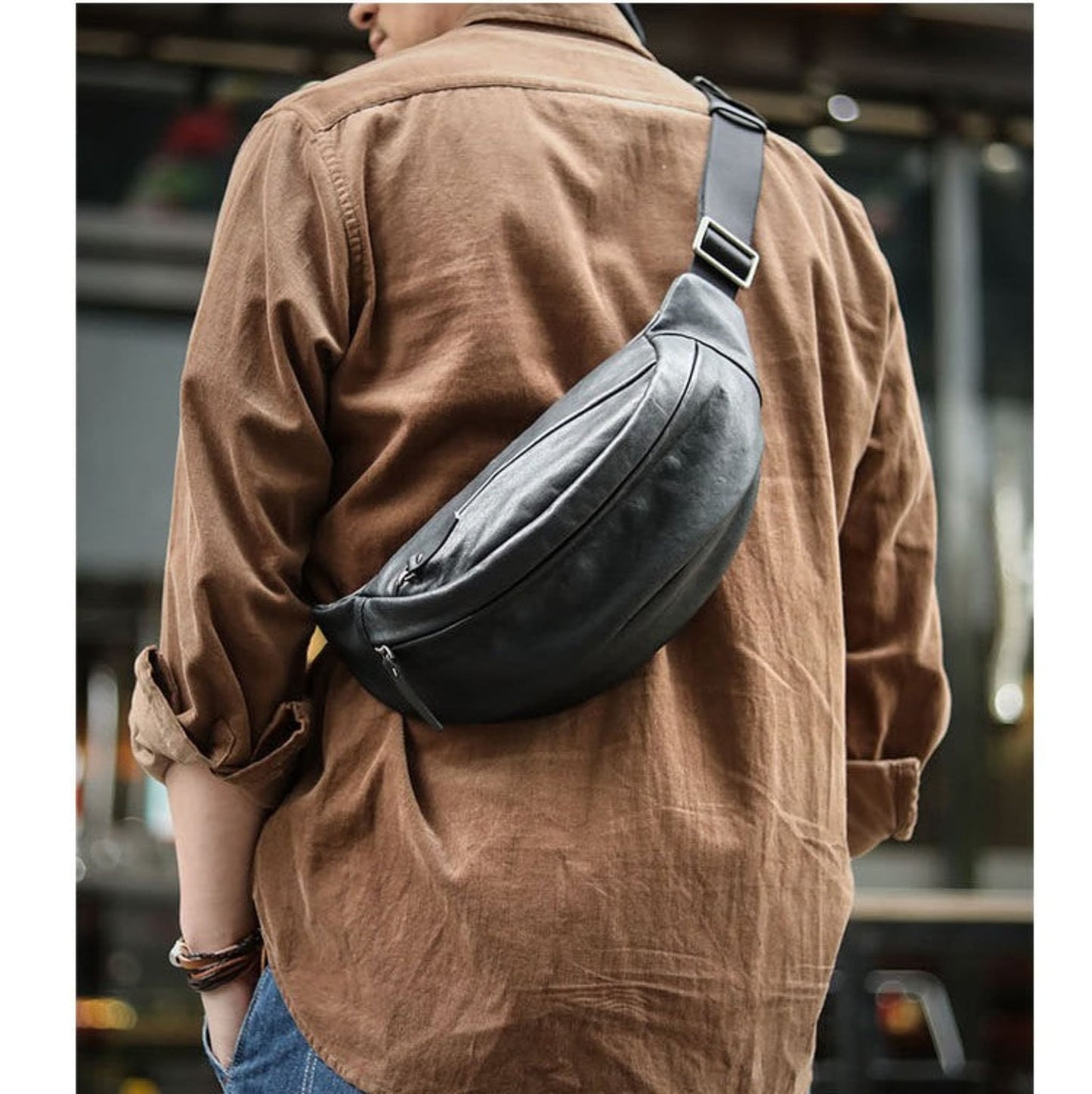 Man wearing black plant-tanned cow leather crossbody mobile phone bag on back with adjustable strap shown from rear in urban setting — Avenue