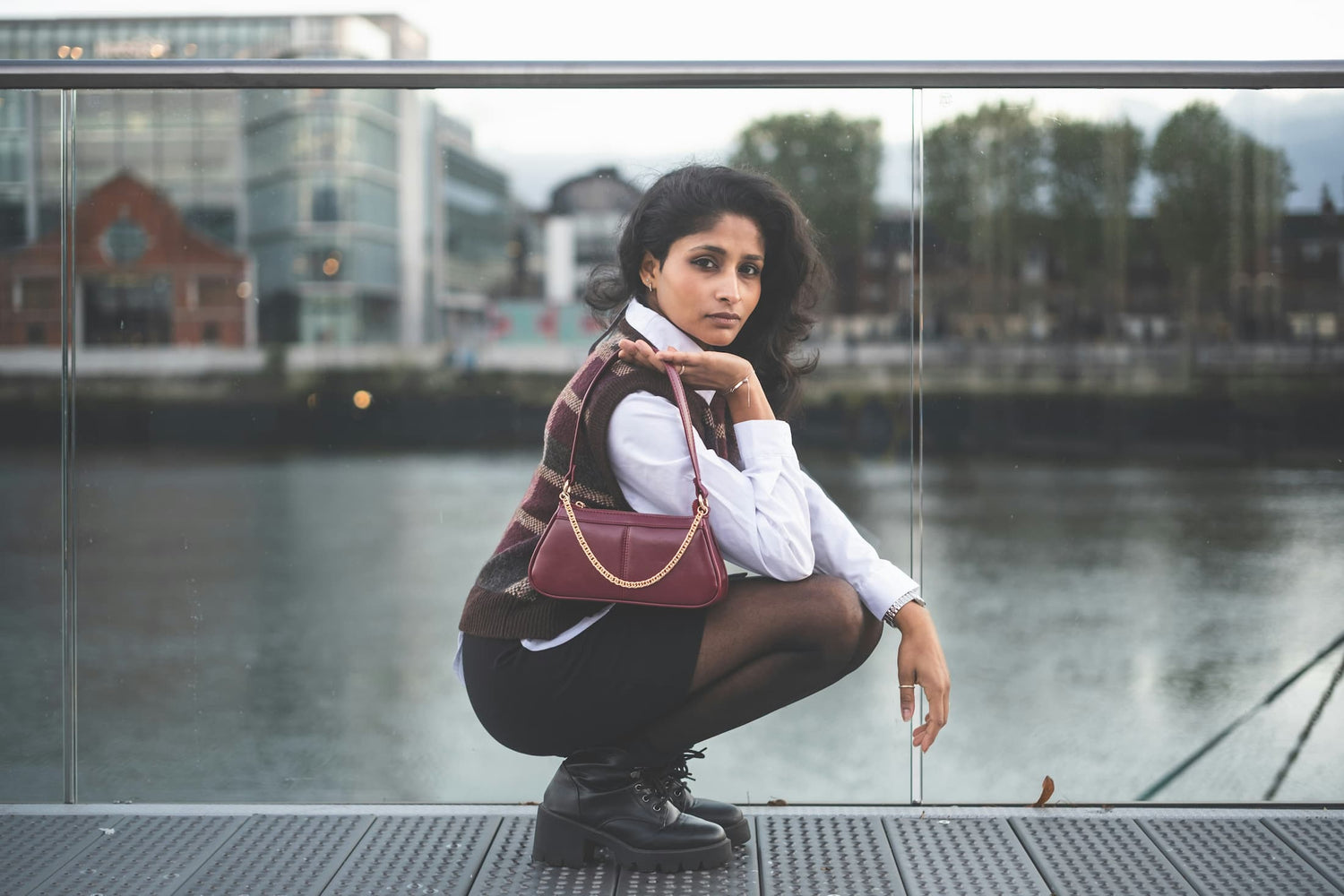 Woman crouching by waterfront carrying burgundy leather shoulder bag — Avenue Special Offers