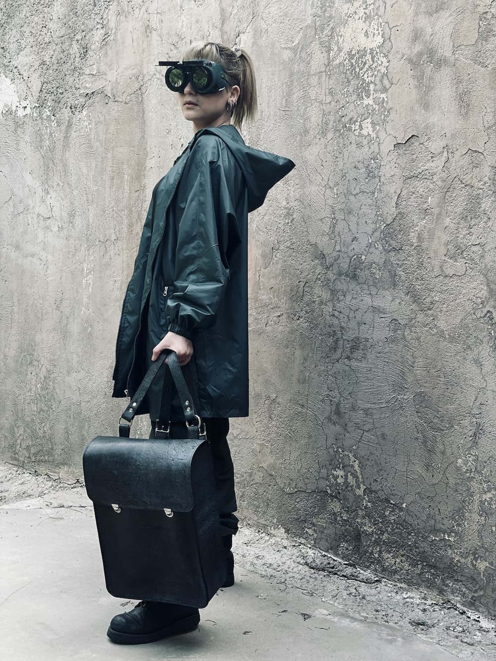 Woman holding premium black structured bag against textured wall — Avenue New Arrivals