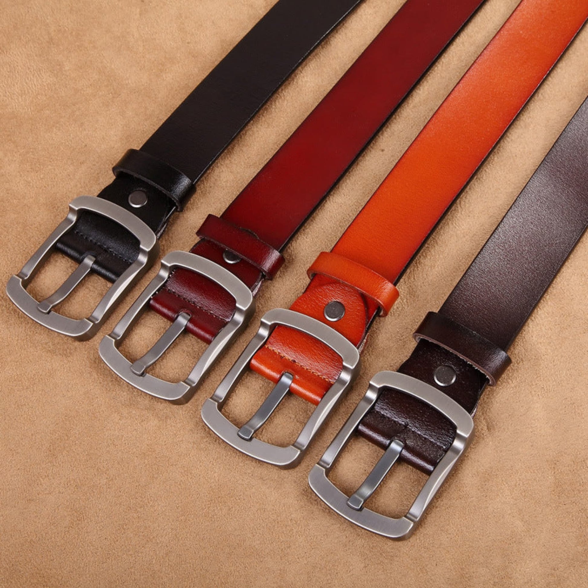 Avenue Men's Genuine Cowhide Leather Retro Belt in all four colors — Black, Brown, Camel and Coffee — with brushed gunmetal pin buckles, flat lay on tan leather background
