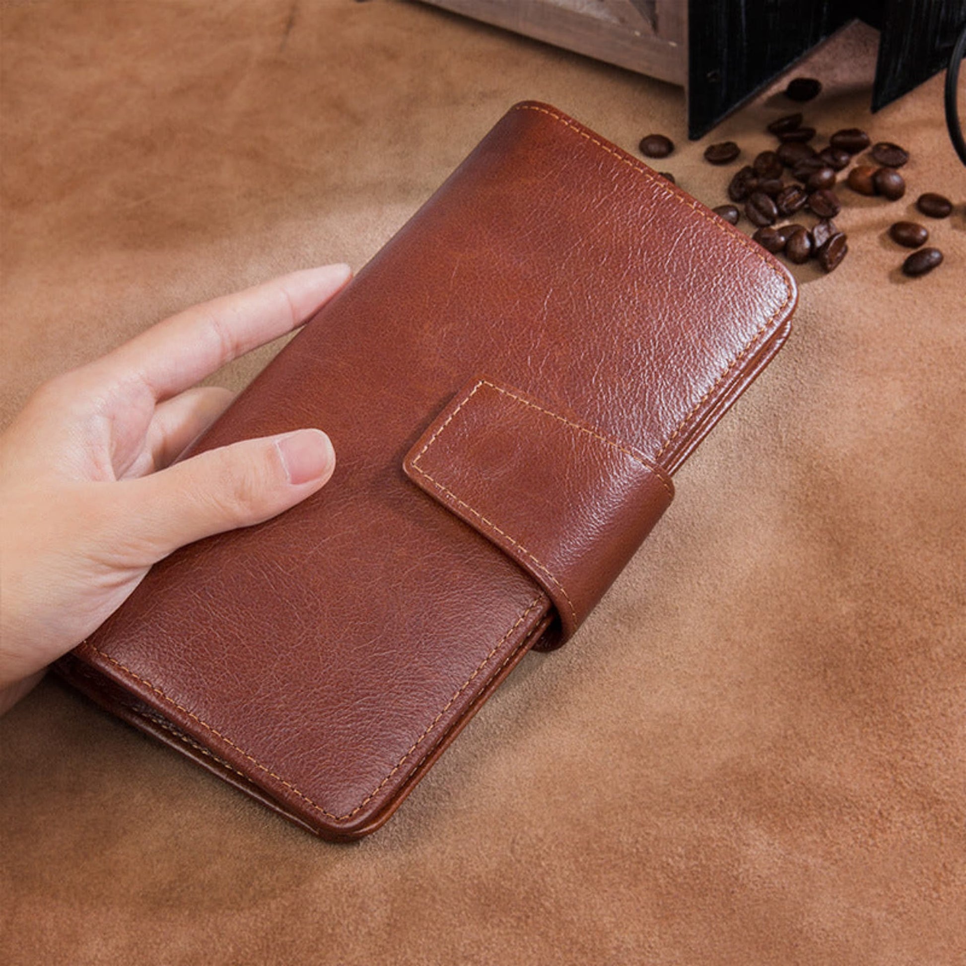 Men's premium RFID protected Maroon hand holding long leather wallet on brown surface lifestyle shot | Avenue