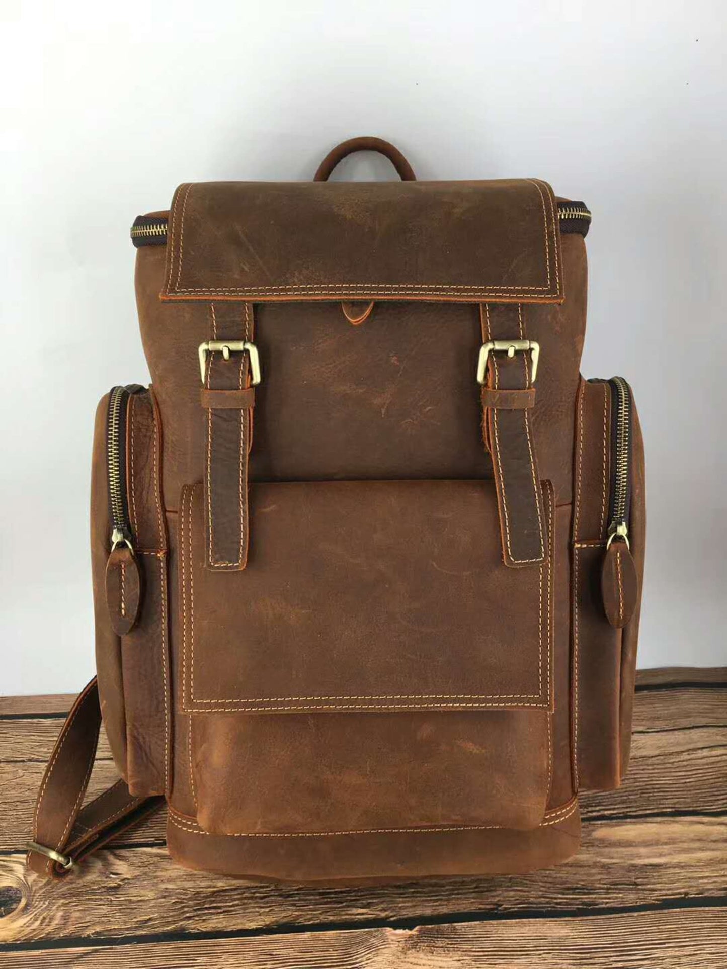 Retro crazy horse leather Men's laptop backpack large capacity in light brown on wooden surface and grey background – front view | Avenue