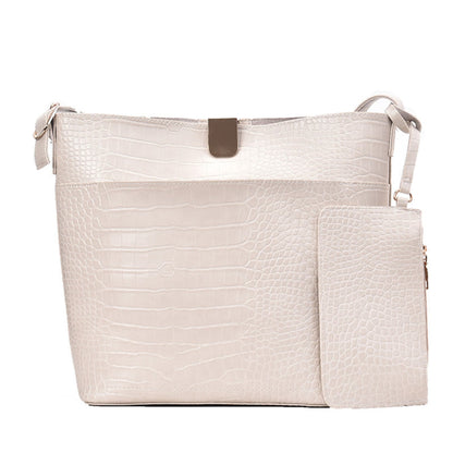Women's one shoulder bucket bag in white, croc-embossed PU leather with magnetic snap closure, attached mini pouch and silver hardware, white background | Avenue