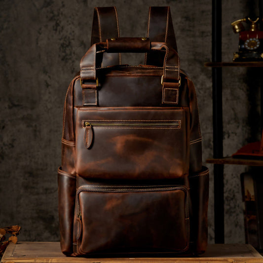 Unisex handmade retro crazy horse leather oversized backpack in brown, front view on wooden surface against dark vintage background showing natural leather patina | Avenue