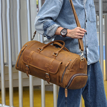 Man wearing Avenue’s brown Top-Grain Cowhide Leather Travel Duffle Bag over his shoulder outdoors against a modern railing background.