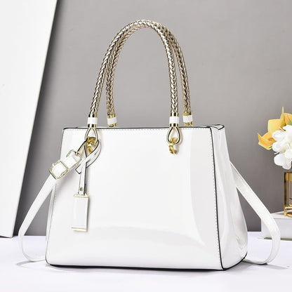 White glossy patent leather shoulder bag with gold accents on a white surface and grey background | Avenue