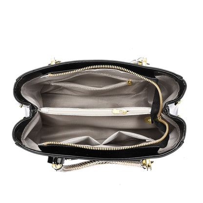 Black glossy patent leather shoulder bag with gold accents, interior view on a white background | Avenue