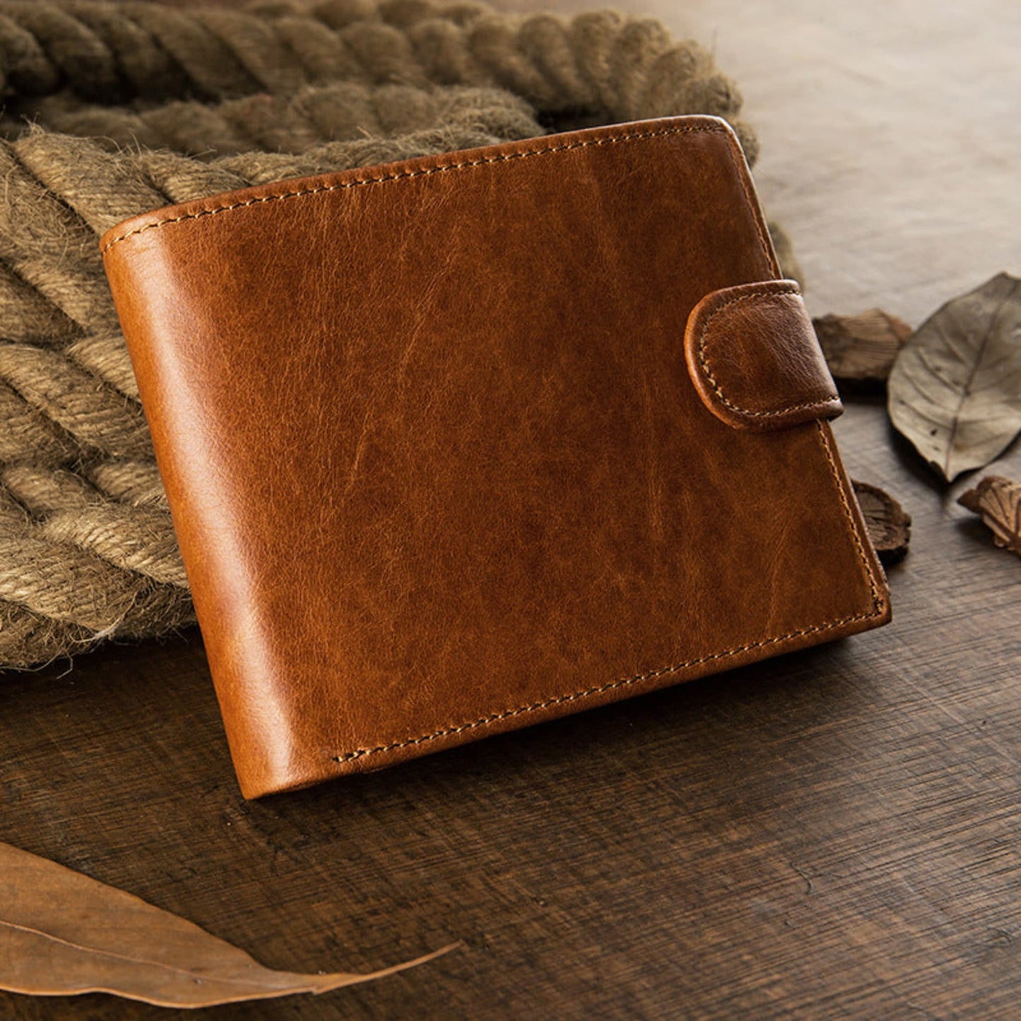 Avenue Men's Short Leather Wallet – Genuine Cowhide in Brown, front angled view with snap closure, displayed on rustic rope and wooden surface