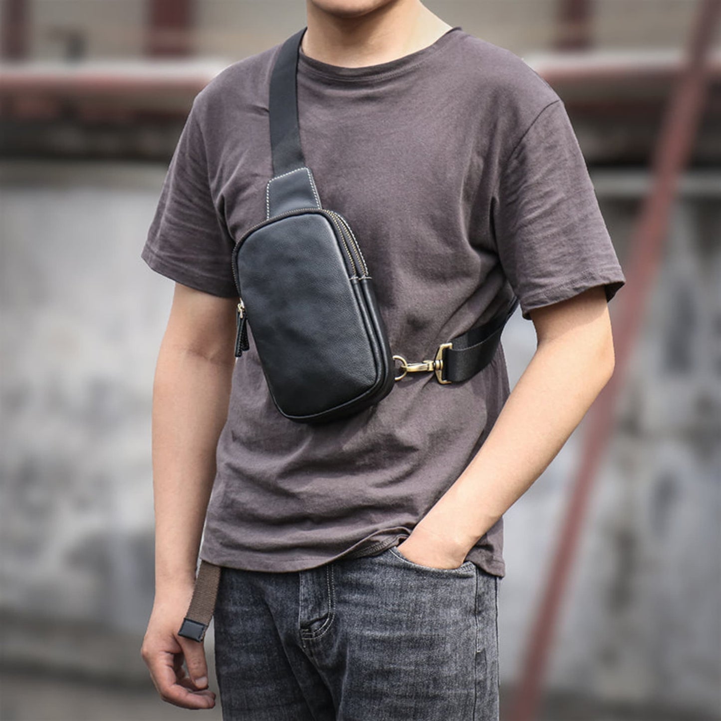Man wearing Men's premium leather chest crossbody bag in black on chest with gold zipper and adjustable strap — Avenue