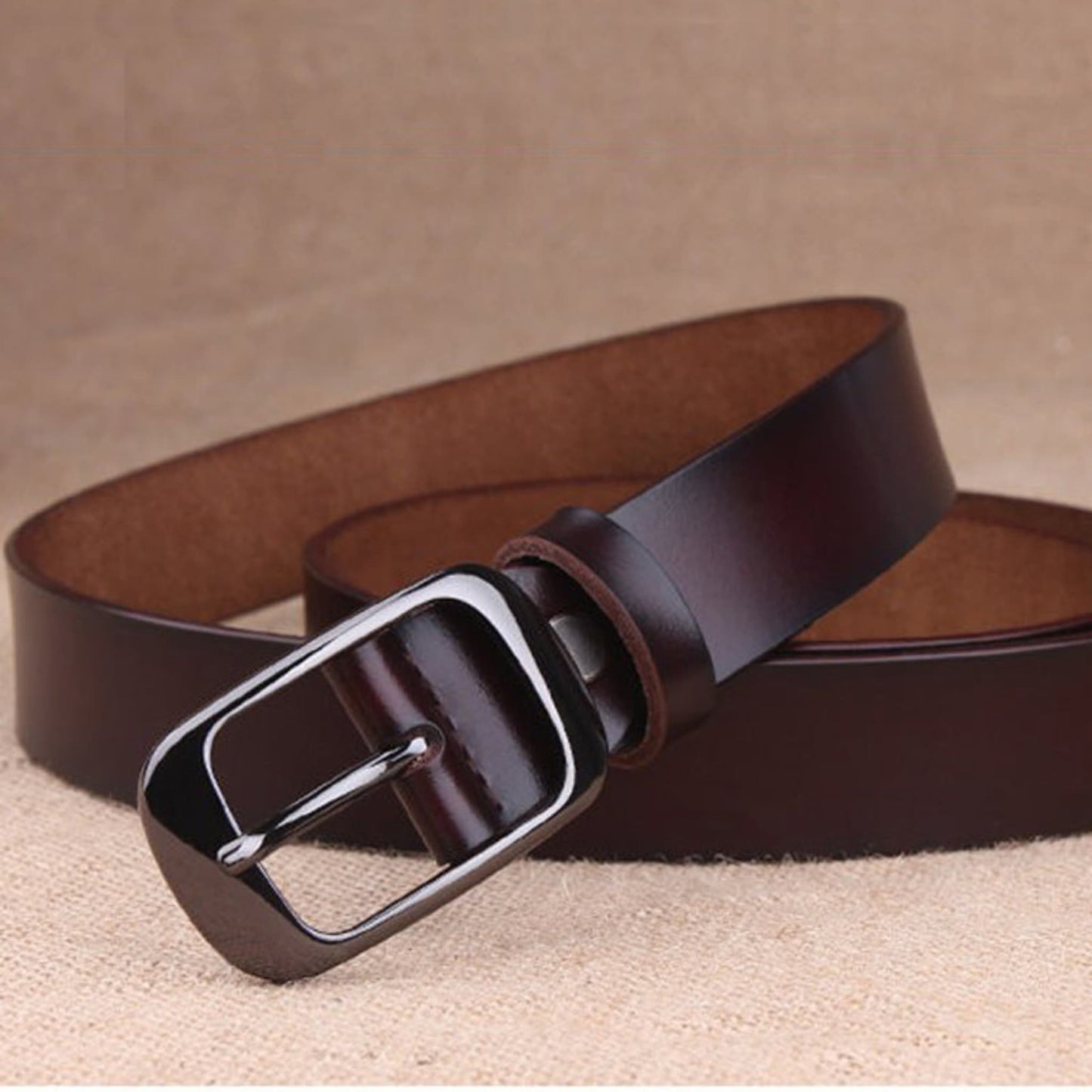 Women's brown leather fashion belt with black buckle, diagonal layered display with buckle in foreground – Avenue