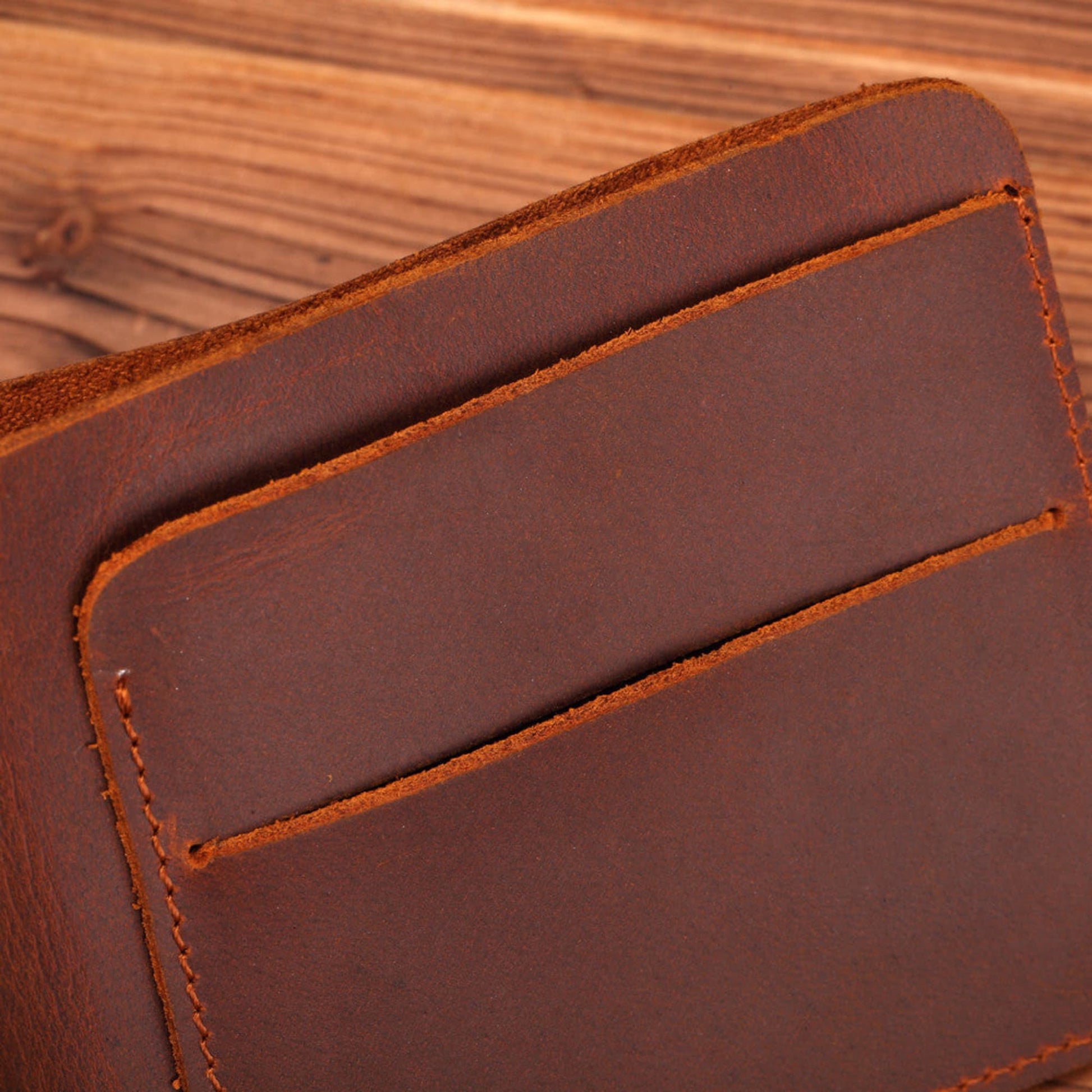 Men's Handmade Crazy Horse Leather Wallet in brown — close-up of exterior card slot with hand-stitched orange thread detailing on a wooden surface | Avenue
