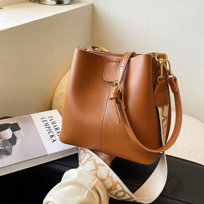 Avenue Wide Shoulder Strap Bucket Bag for Women in Brown - PU Leather Crossbody Bag Front View with Adjustable Patterned Shoulder Strap and Gold Hardware