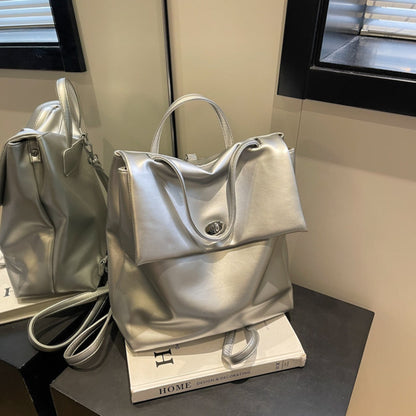 Women's Retro Flap Backpack in Silver – Lifestyle Shot with Mirror Reflection, Turn-Lock Closure and Top Handle Displayed on Books | Avenue