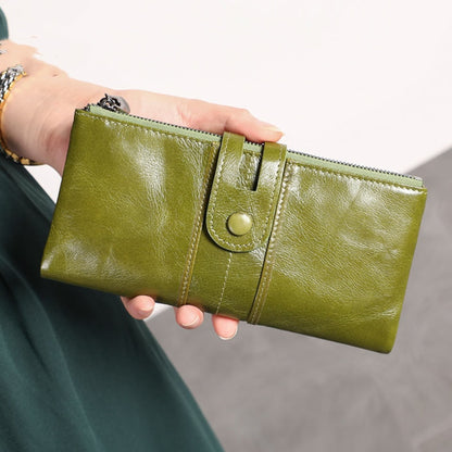Women's RFID Long Leather Wallet first layer cowhide in Green – woman holding upright showing full front with strap closure and zipper | Avenue