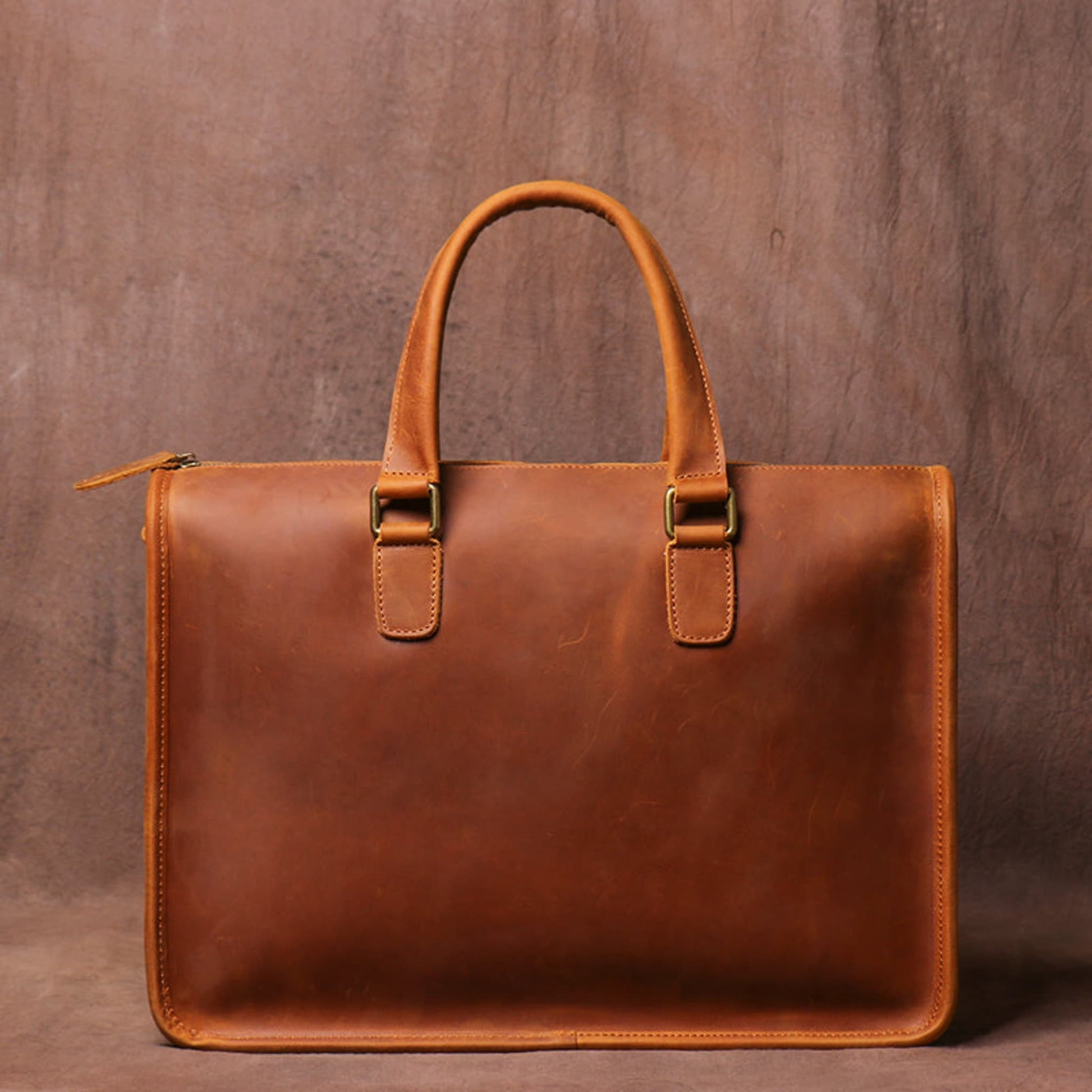 Men's Crazy Horse Leather Briefcase | Vintage Laptop Bag – Vintage Brown Front View with Top Handle, Antique Brass Hooks and Side Zipper Closure on Vintage Brown Textured Background by Avenue
