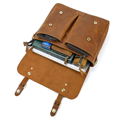 Men's Crazy Horse Leather Crossbody Bag – Top Layer Cowhide Messenger Bag in Brown, overhead view on white background showing open flap with brass studs and packed contents including laptop, books, phone, wallet and zipper pouch demonstrating full capacity | Avenue