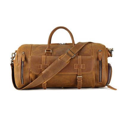 Front view of Avenue’s brown Top-Grain Cowhide Leather Travel Duffle Bag with twin handles, adjustable shoulder strap, buckle-secured flap pocket, and side zipper pockets on a white background.