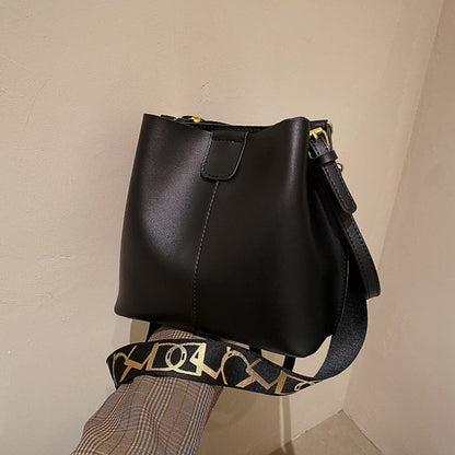 Avenue Wide Shoulder Strap Bucket Bag for Women in Black - PU Leather Crossbody Bag Side View with Adjustable Patterned Shoulder Strap and Gold Hardware