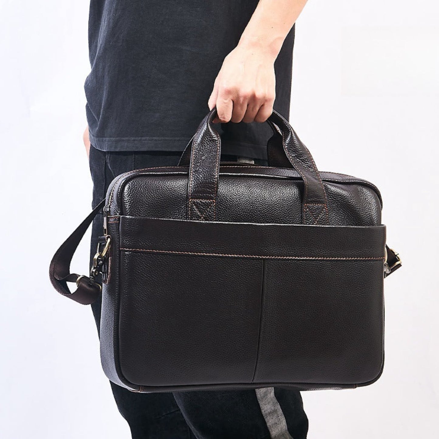 Men's Genuine Leather Crossbody Bag in Brown – Lifestyle Shot of Man Carrying Bag by Top Handle with Detachable Shoulder Strap Visible | Avenue