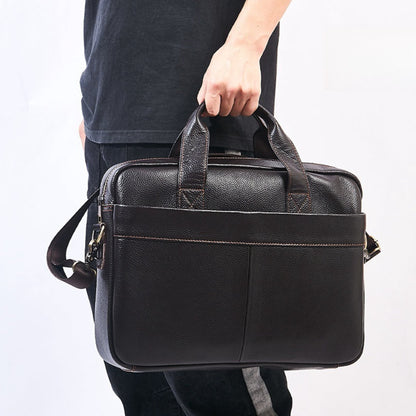 Men's Genuine Leather Crossbody Bag in Brown – Lifestyle Shot of Man Carrying Bag by Top Handle with Detachable Shoulder Strap Visible | Avenue