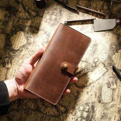 Avenue Retro Crazy Horse Leather Long Wallet in Brown – Unisex Genuine Leather Wallet with Brass Snap Closure, held in hand against a vintage world map with leather crafting tools