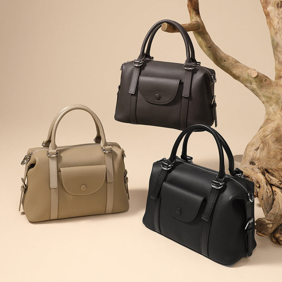 Three Avenue Women’s Genuine Leather Shoulder Handbags in Black, Brown, and Elephant Gray, displayed with top handles and front flaps against a beige background with a wooden branch.