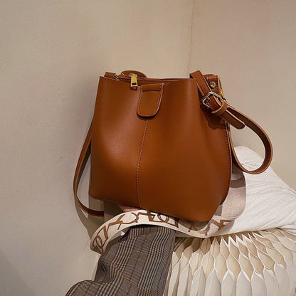 Avenue Wide Shoulder Strap Bucket Bag for Women in Coffee - PU Leather Crossbody Bag Front View with Adjustable Patterned Shoulder Strap and Gold Hardware
