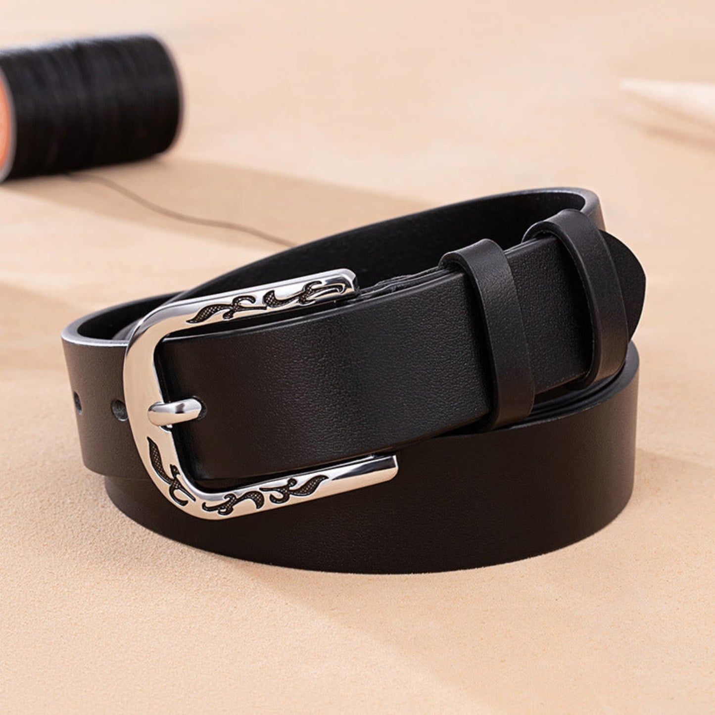Women's Slim Black Leather Belt Coiled on Sandy Surface with Engraved Floral Silver D-Buckle – Avenue