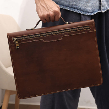 Avenue Men's Crazy Horse Leather Laptop Briefcase 13.3 Inch — Man Holding Briefcase by Top Handle Showing Back Zipper Pocket and Contrast Stitching in Coffee Brown