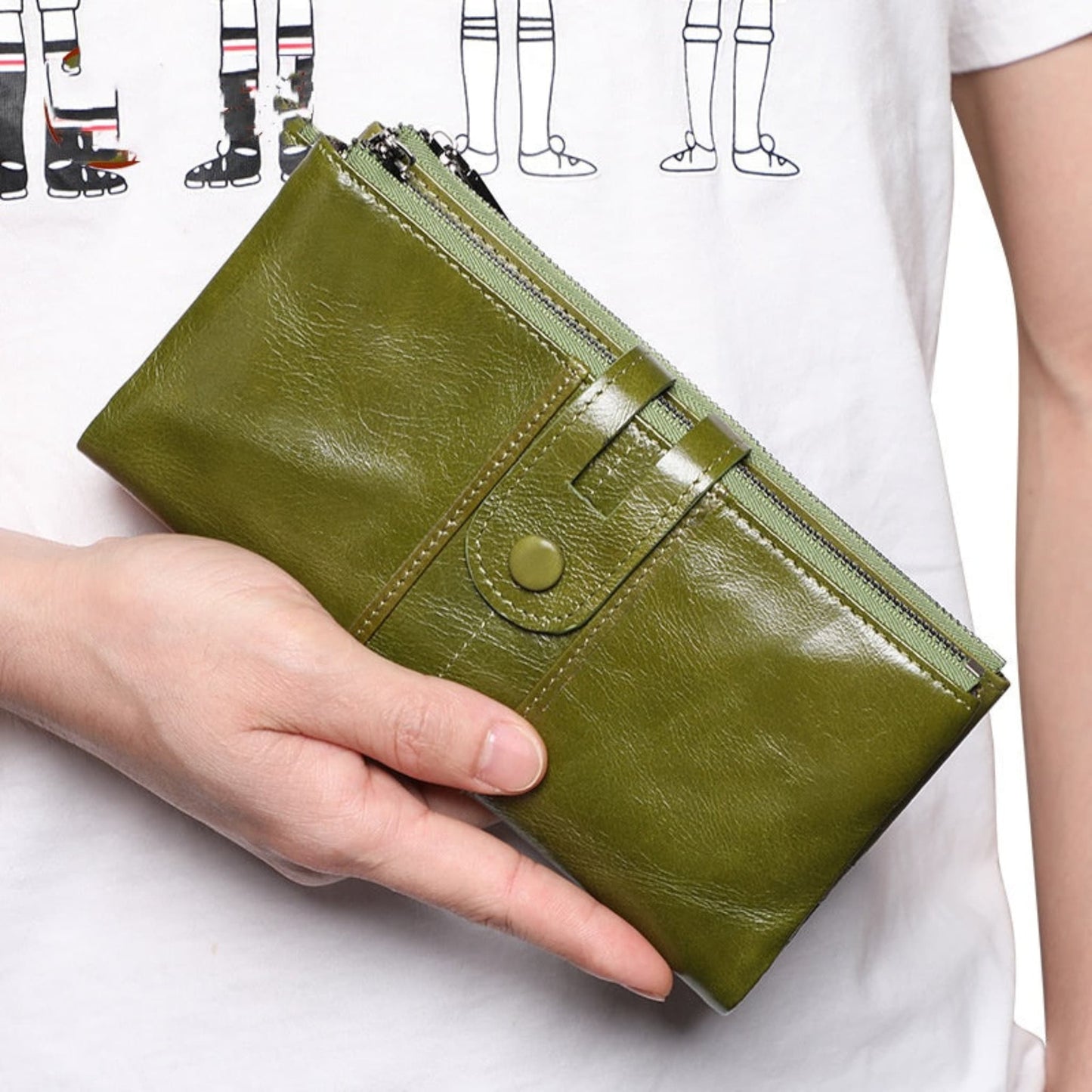 Women's RFID Long Leather Wallet first layer cowhide in Green – hand-held front view showing strap closure and zipper | Avenue